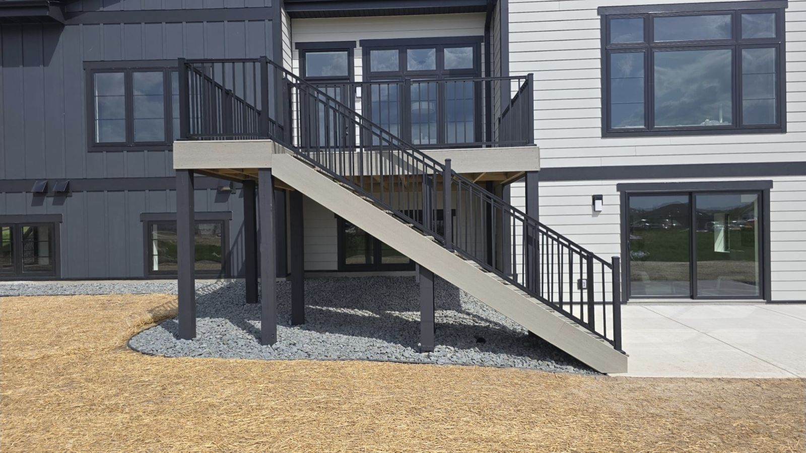 Composite deck with black railing and stairs to the lower-level patio