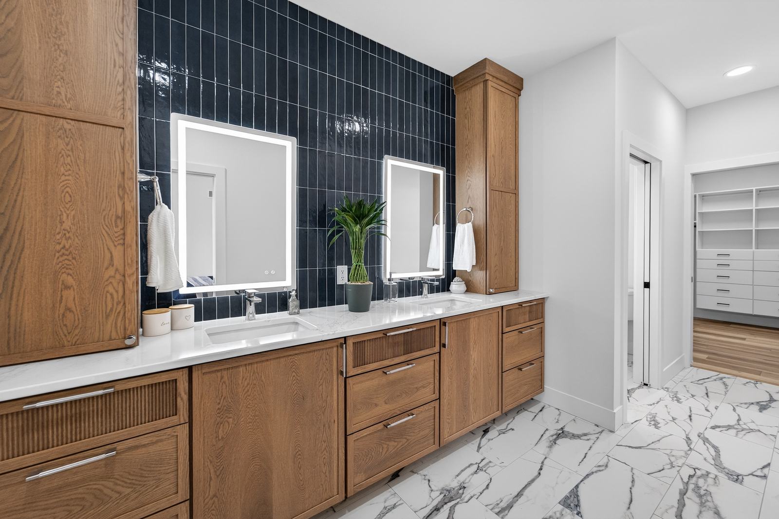 Primary bath with navy tile and lit mirrors